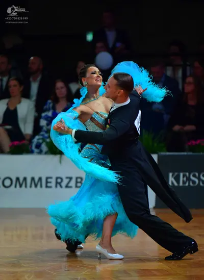 Dancesport competitor: Female dancer: light blue Latin dress with extensive turquoise feather trim on t