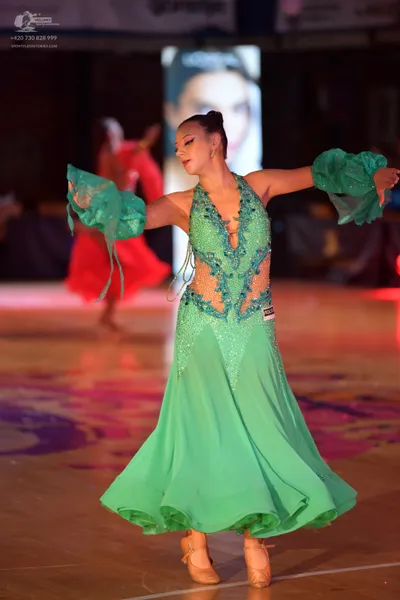 Dancesport competitor: Female dancer in foreground: mint green ballroom gown with a sequin-embellished 