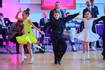 Dancesport competitor: Female dancer (left): yellow latin dress, sleeveless, short flared skirt