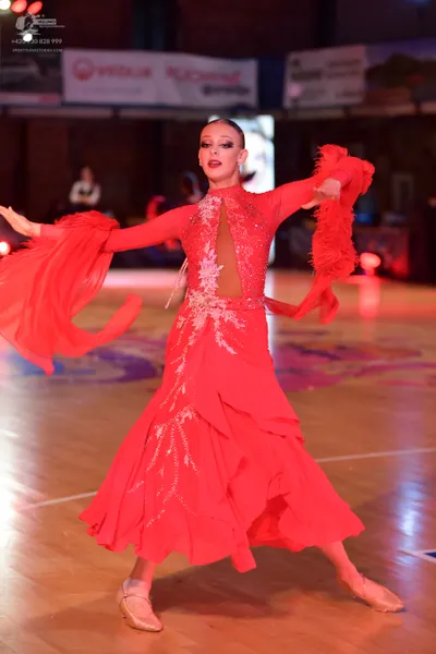 Dancesport competitor: Female dancer: red latin dance dress with long sleeves, large flowing ruffled cu