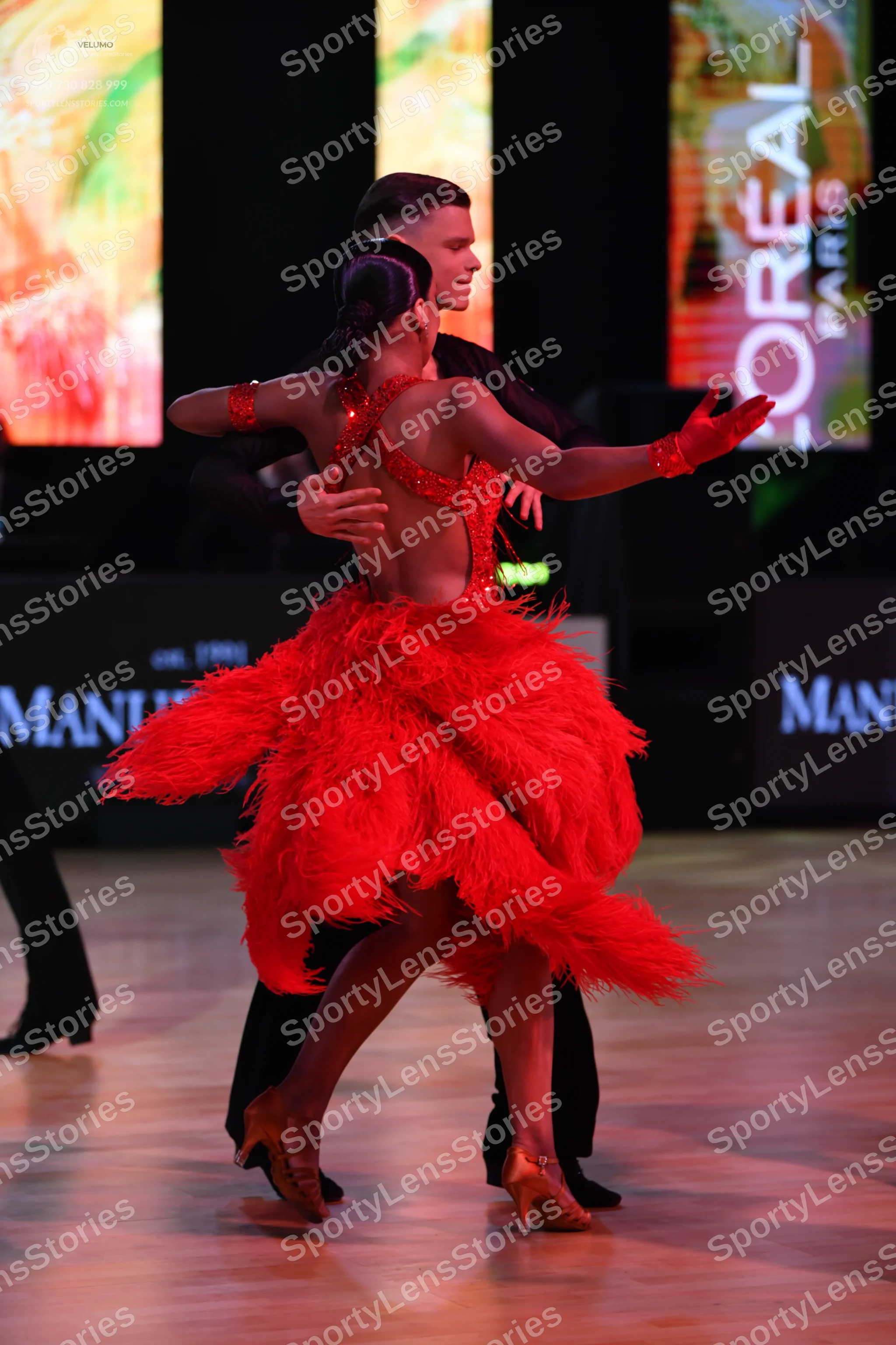 Dancesport competitor: Female dancer: red latin dress with a sequined bodice and a voluminous feathered