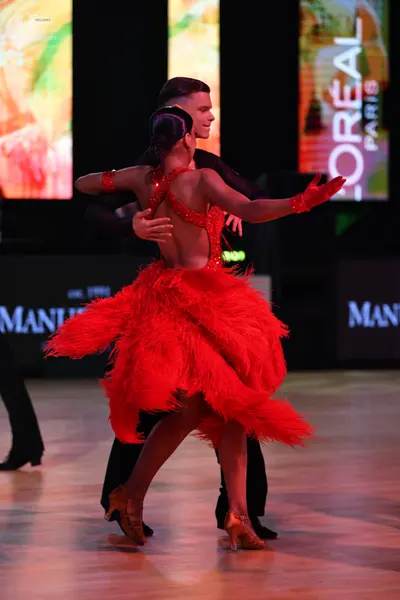 Dancesport competitor: Female dancer: red latin dress with a sequined bodice and a voluminous feathered