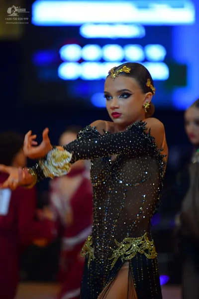 Dancesport competitor: Main female dancer: black latin dress with long sleeves, sheer mesh panels, and 