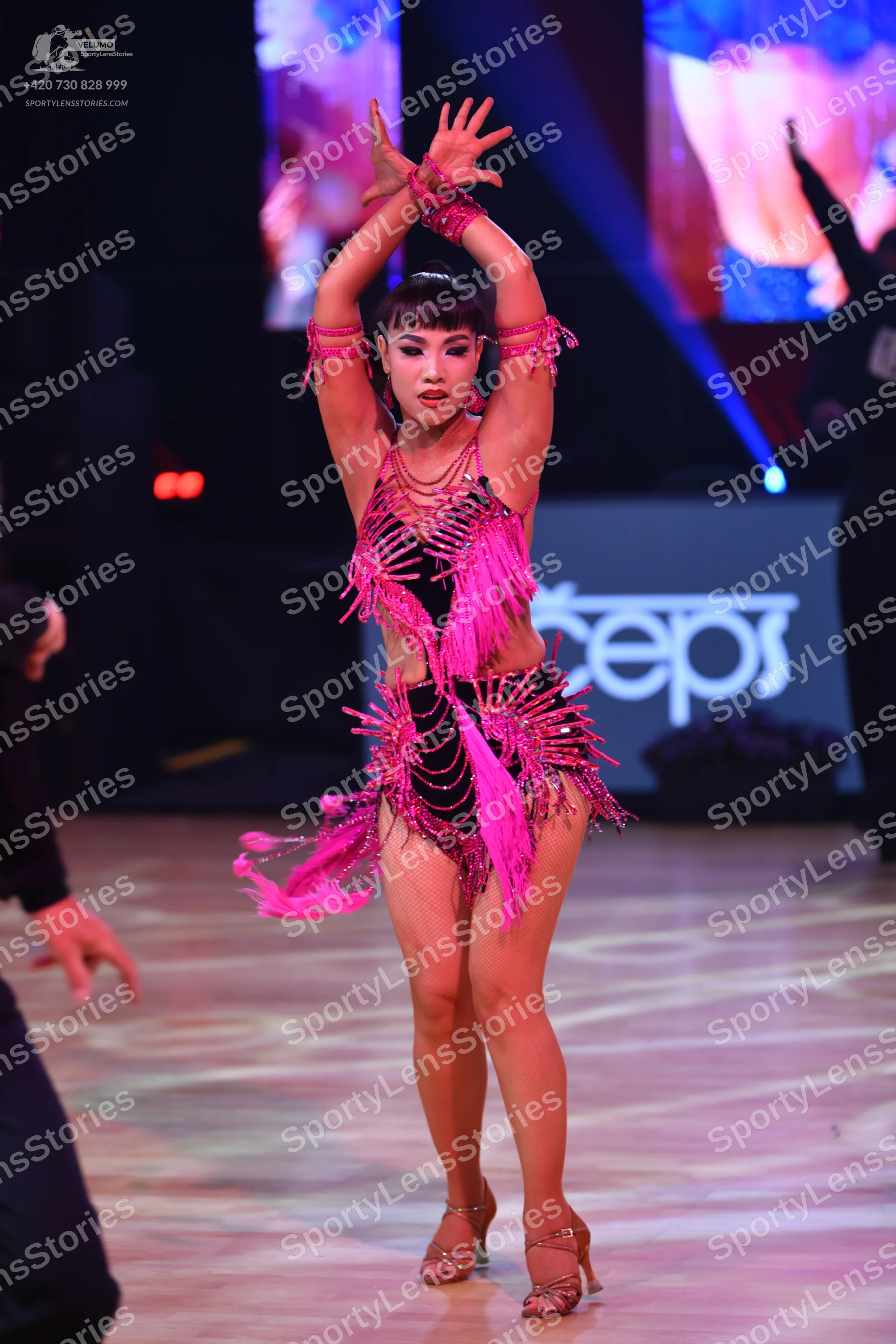 Dancesport competitor: Female dancer: black and bright pink Latin dance costume with heavy pink fringe,
