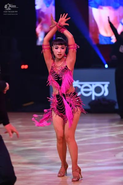 Dancesport competitor: Female dancer: black and bright pink Latin dance costume with heavy pink fringe,