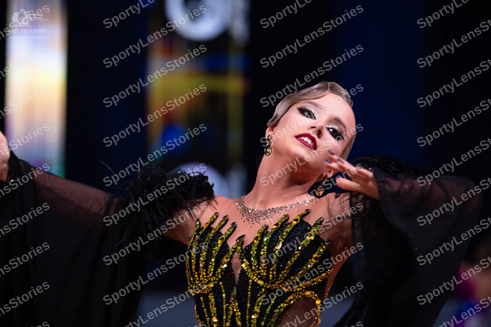 Dancesport competitor: Female dancer: black Latin dance dress with gold sequin patterns on the bodice,