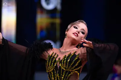 Dancesport competitor: Female dancer: black Latin dance dress with gold sequin patterns on the bodice, 