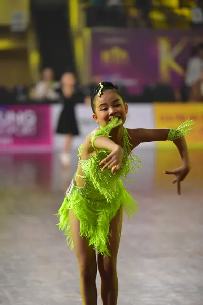Dancesport competitor: Female dancer: neon green Latin dance costume with long fringe