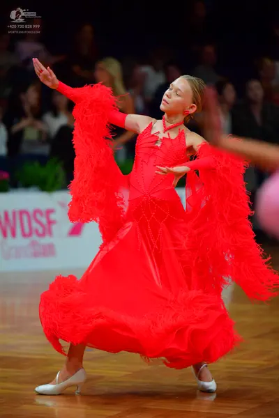 Dancesport competitor: Female dancer: red ballroom dress with large feather-like or fringe embellishmen
