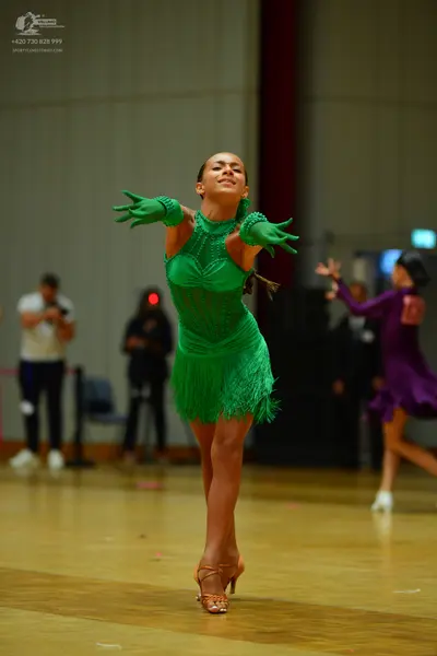 Dancesport competitor: Female dancer: green latin dress with fringe and matching long gloves