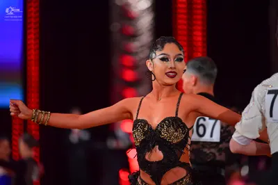 Dancesport competitor #67: Female dancer: black and gold sequined Latin dress with cutouts and thin straps