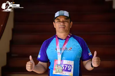 Marathon runner #579: Runner 1: blue and purple jersey, white and grey cap, medal, black watch