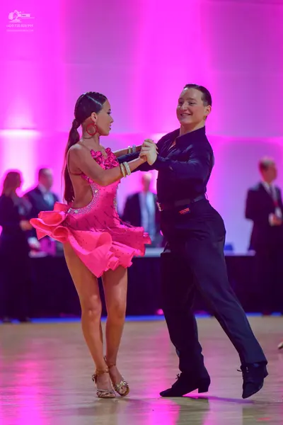 Dancesport competitor: Female dancer: pink Latin dance dress with a ruffled skirt and spaghetti straps