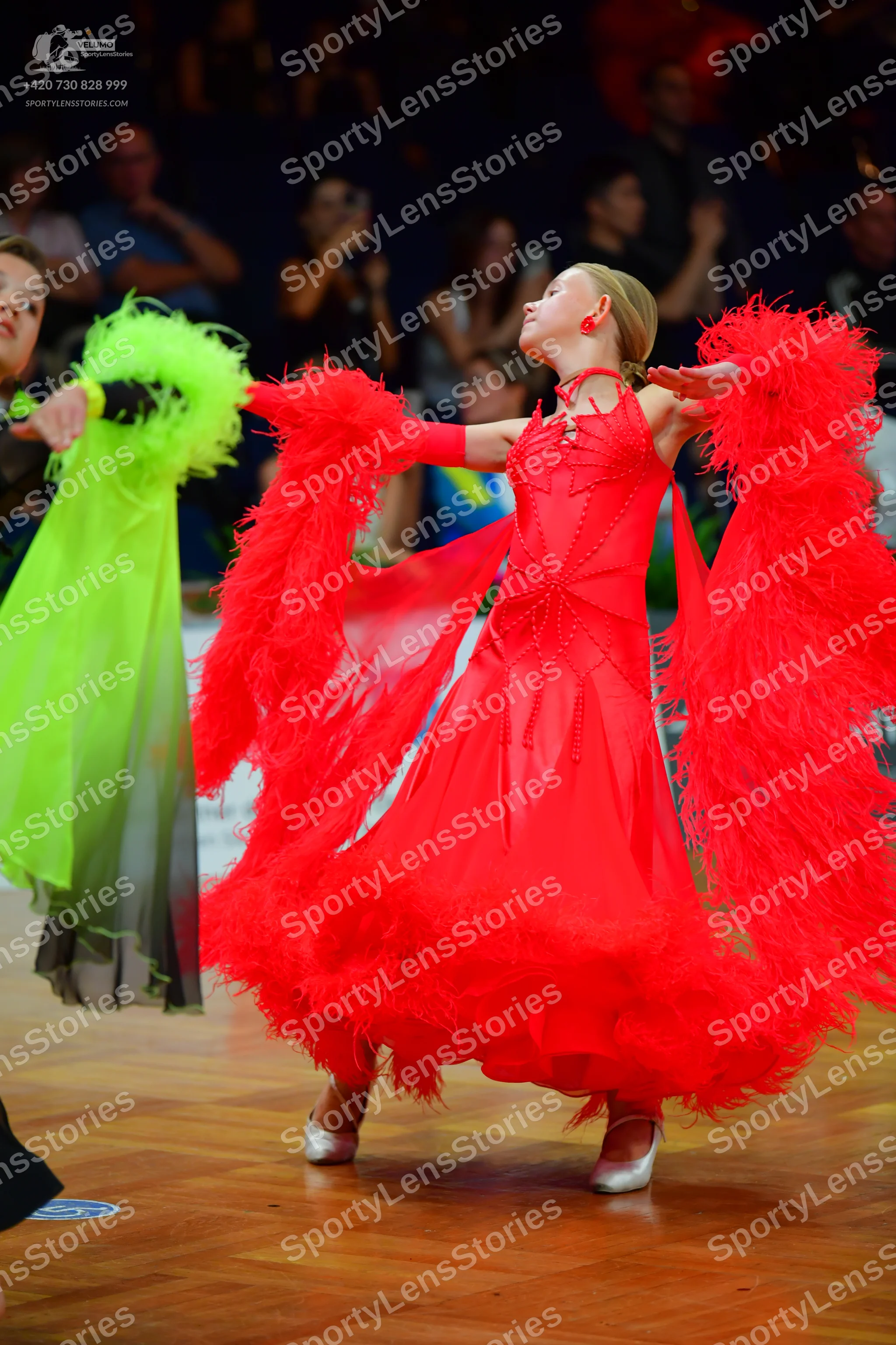 Dancesport competitor: Female dancer 1: red Latin dress with large, voluminous, feather-like fringe on