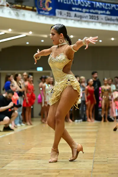 Dancesport competitor: Main dancer: gold/champagne-colored sequined Latin dress with side cutouts and f