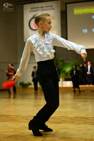 Dancesport competitor: Male dancer: white long-sleeved shirt with ruffles on the front and cuffs, and b