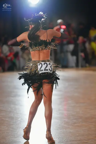Dancesport competitor #223: Female dancer: black and gold sequined Latin dance costume with a crop top and a