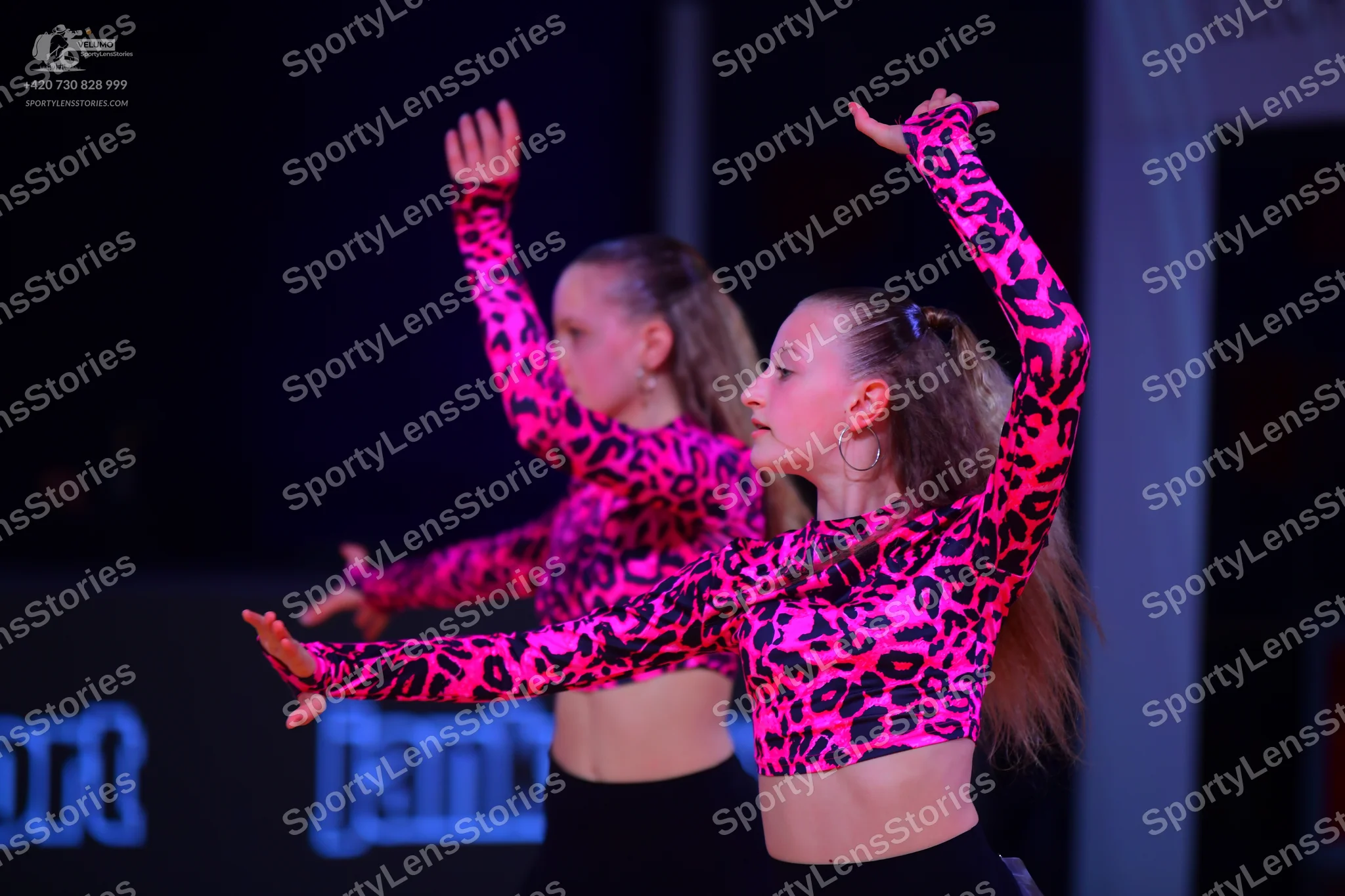 Dancesport competitor: Two female dancers are wearing matching costumes consisting of long-sleeved pink