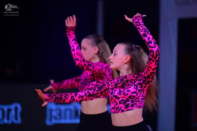 Dancesport competitor: Two female dancers are wearing matching costumes consisting of long-sleeved pink