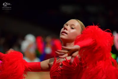 Dancesport competitor: Female dancer: red latin dress with large red feathers on the sleeves