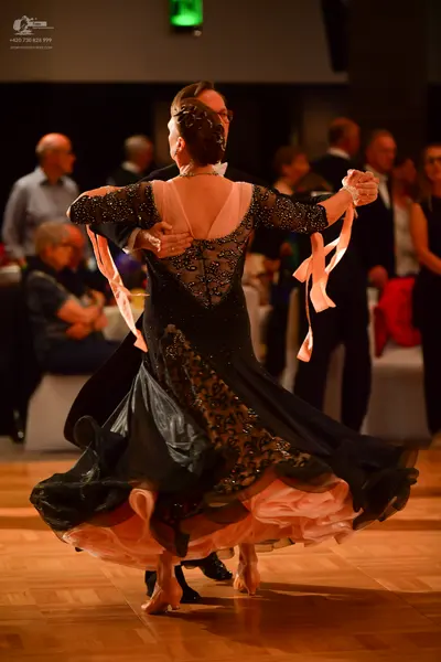 Dancesport competitor: Female dancer: black ballgown with black lace or sequin embellishments, a sheer 