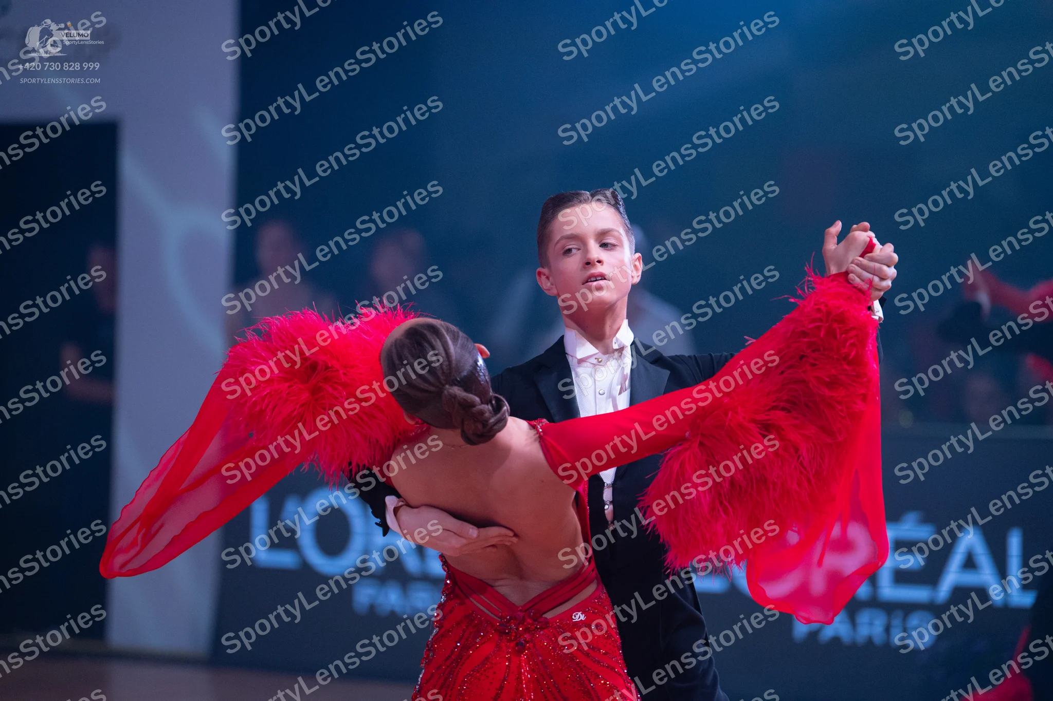 Dancesport competitor: Female dancer: red Latin dress with voluminous, feathery red sleeves and sequin