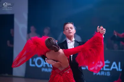 Dancesport competitor: Female dancer: red Latin dress with voluminous, feathery red sleeves and sequin 