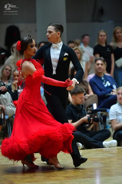 Dancesport competitor: Female dancer: long red ballroom dress with feathers around the skirt and sleeve