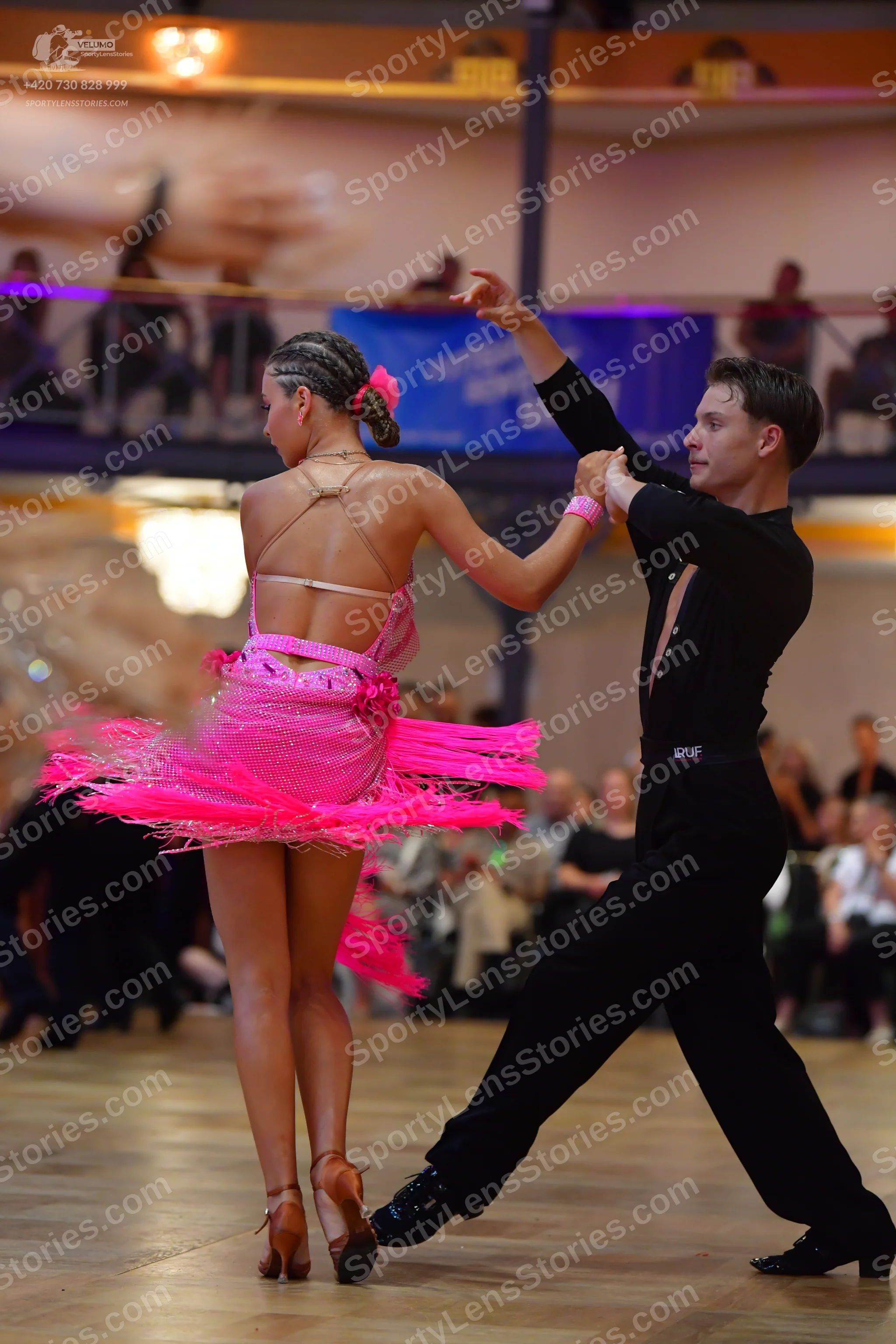 Dancesport competitor: Female dancer: bright pink Latin dress with many layers of fringe and sequin emb
