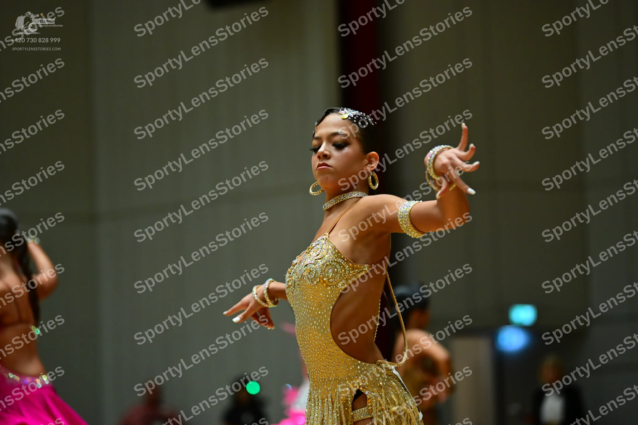 Dancesport competitor: Female dancer in center: gold sequin and crystal Latin dress with side cut-outs,