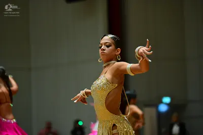 Dancesport competitor: Female dancer in center: gold sequin and crystal Latin dress with side cut-outs,
