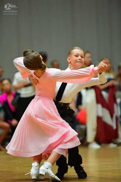 Dancesport competitor: Female dancer: light pink long-sleeved ballroom dress with a flowing, pleated sk