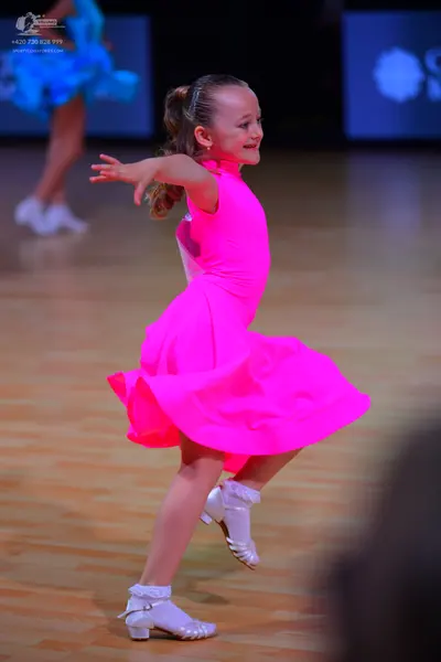 Dancesport competitor: Female dancer: bright pink, sleeveless, high-neck dress with a flared skirt, pai