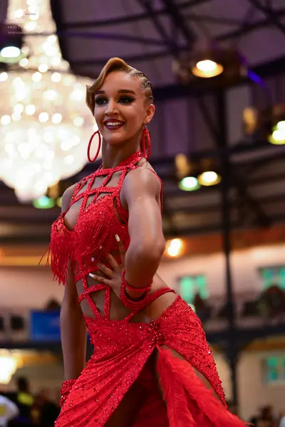 Dancesport competitor: Female dancer: red latin dress with sequins and fringe, featuring cutouts and la