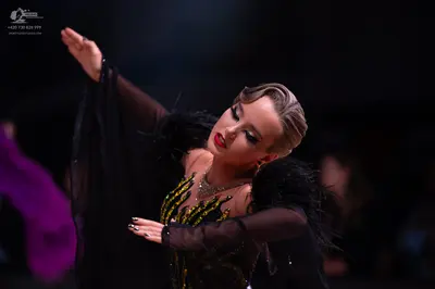 Dancesport competitor: Female dancer: black latin dress with yellow/gold sequin pattern, sheer black sl