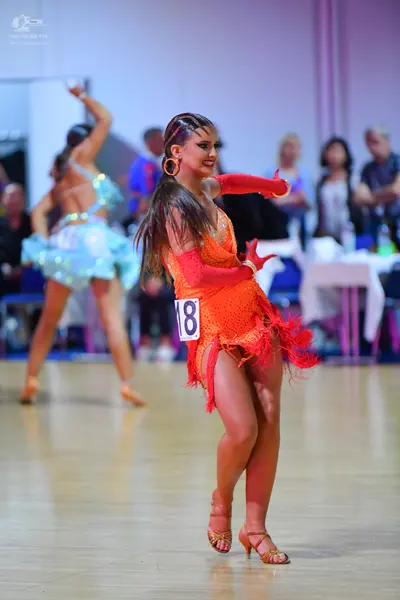 Dancesport competitor #18: Female dancer in foreground: orange latin dress with sequins, fringe, and long s