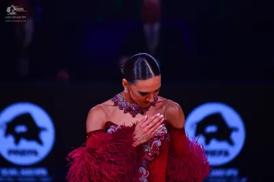 Dancesport competitor: Female dancer: red/maroon Latin-style dress with heavy sequin and bead embellish