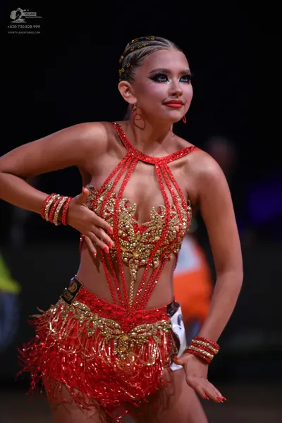 Dancesport competitor: Female dancer: red Latin dance dress with gold sequin embellishments on the bodi