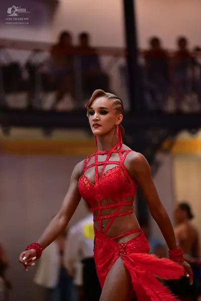 Dancesport competitor: Female dancer: red sequined Latin dance dress with cut-out straps, a high slit, 