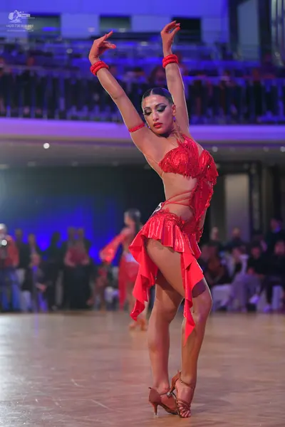 Dancesport competitor: Female dancer: red latin dress with fringe, a mesh bodice, and red wristbands