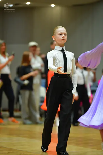 Dancesport competitor: Male dancer: white long-sleeved shirt, black tie, and black trousers