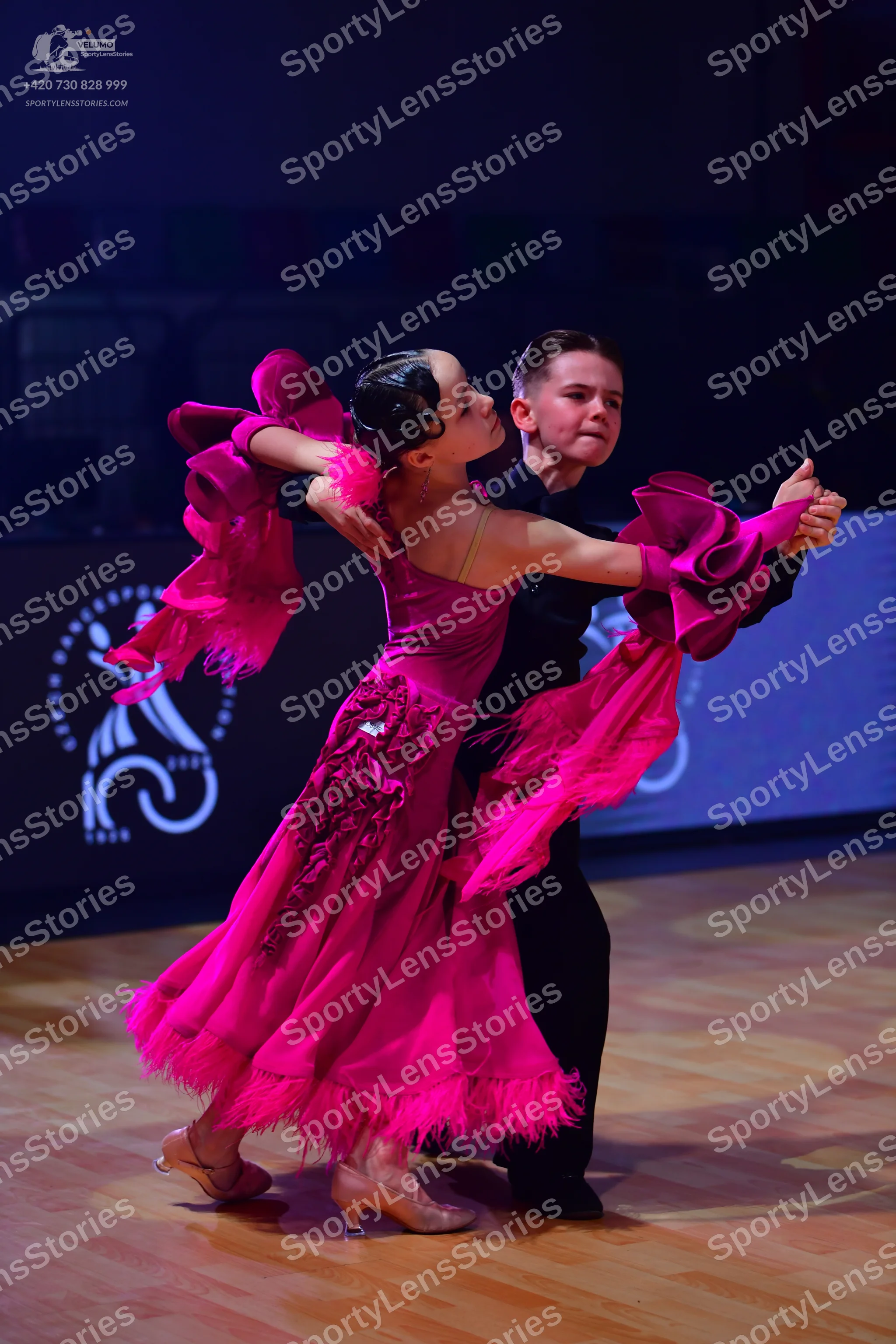 Dancesport competitor: Female dancer: bright pink latin dress with large ruffled sleeves and fringe tri