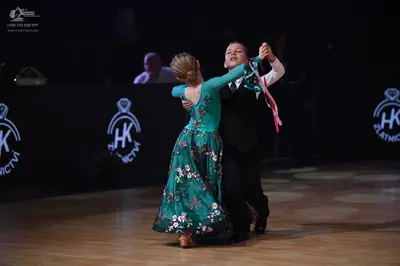 Dancesport competitor: Female dancer: teal long-sleeved ballgown with a floral pattern on the skirt