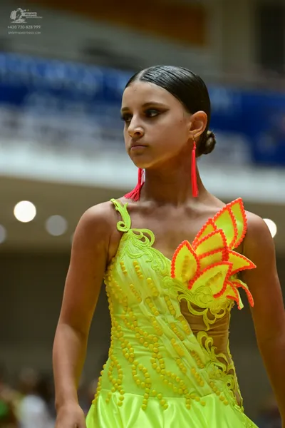 Dancesport competitor: Female dancer: neon yellow latin dress with sequined/beaded patterns, orange/red