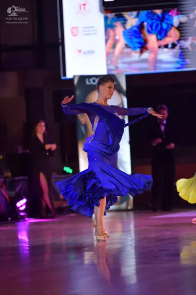 Dancesport competitor: Main female dancer: blue ballroom gown with long sleeves, sequin embellishments 