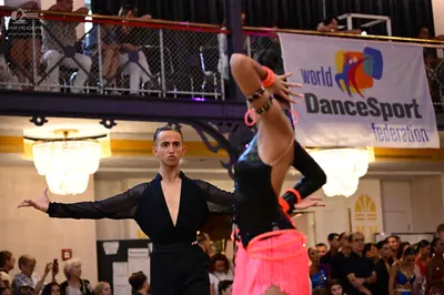 Dancesport competitor: Male dancer: black long-sleeved top with sheer sleeves and black trousers