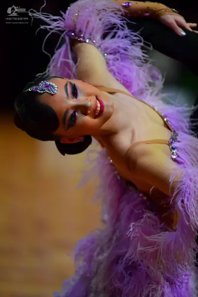 Dancesport competitor: Female dancer: light purple Latin-style dress heavily adorned with feathers and 