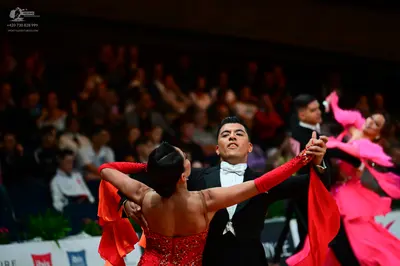 Dancesport competitor: Female dancer in foreground: red latin dress with red flowing fabric on arms and