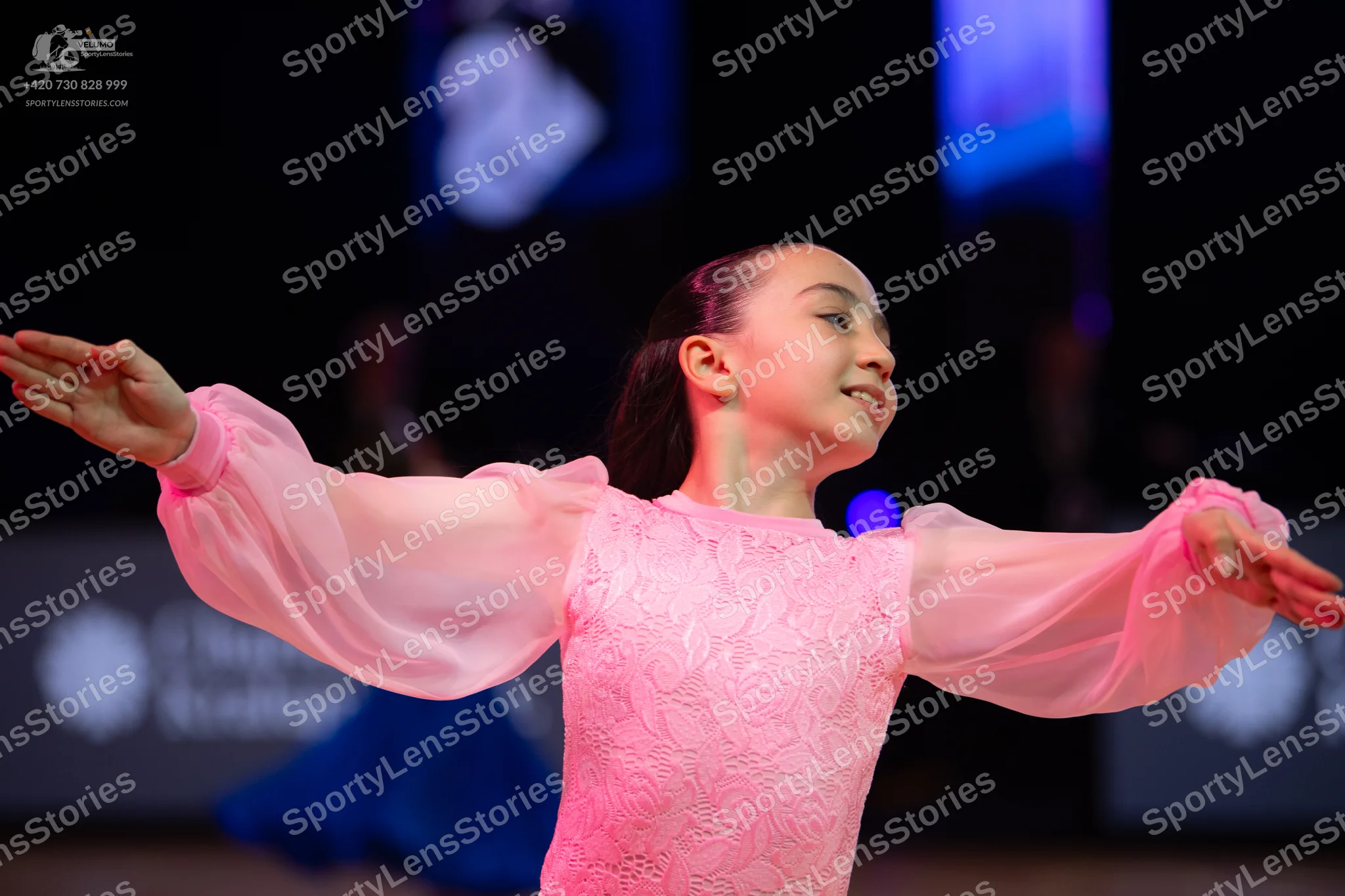 Dancesport competitor: Female dancer in foreground: blush pink ballroom dress with a floral lace bodice