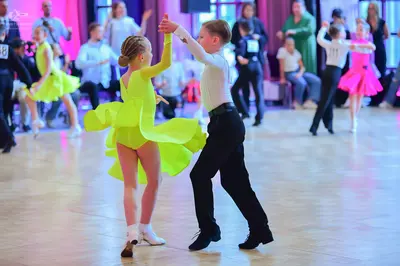 Dancesport competitor #18: Female dancer (foreground): lime green latin dress with a layered, ruffled skirt